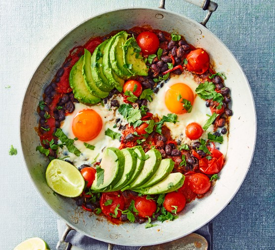 A bowl of eggs with sliced avocados and cherry tomatoes