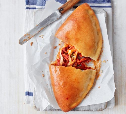 Calzone pizza filled with ham, cheese and tomatoes