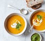 Carrot soup with chilli coriander pesto served in bowls with crusty bread