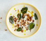 Cauliflower soup with sage leaves and hazelnuts in bowl