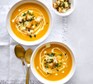 Two bowls of creamy carrot soup with garlicky seeded croutons
