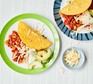 Two plates serving chilli with tacos, avocado and cheese