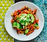 Tomato penne with avocado on a white plate