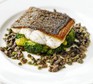 A fillet of pan-fried sea bass on a bed of broccoli and capers