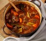 Beef & vegetable stew in a cast iron pot with wooden spoon