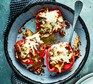 Mediterranean turkey-stuffed peppers topped with grated cheese on a silver dish