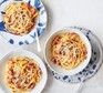 Spaghetti with pancetta and cheese in bowls with cutlery