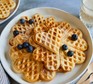 A plate of heart-shaped waffles topped with blueberries