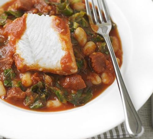White fish with a bean stew in a bowl with a fork